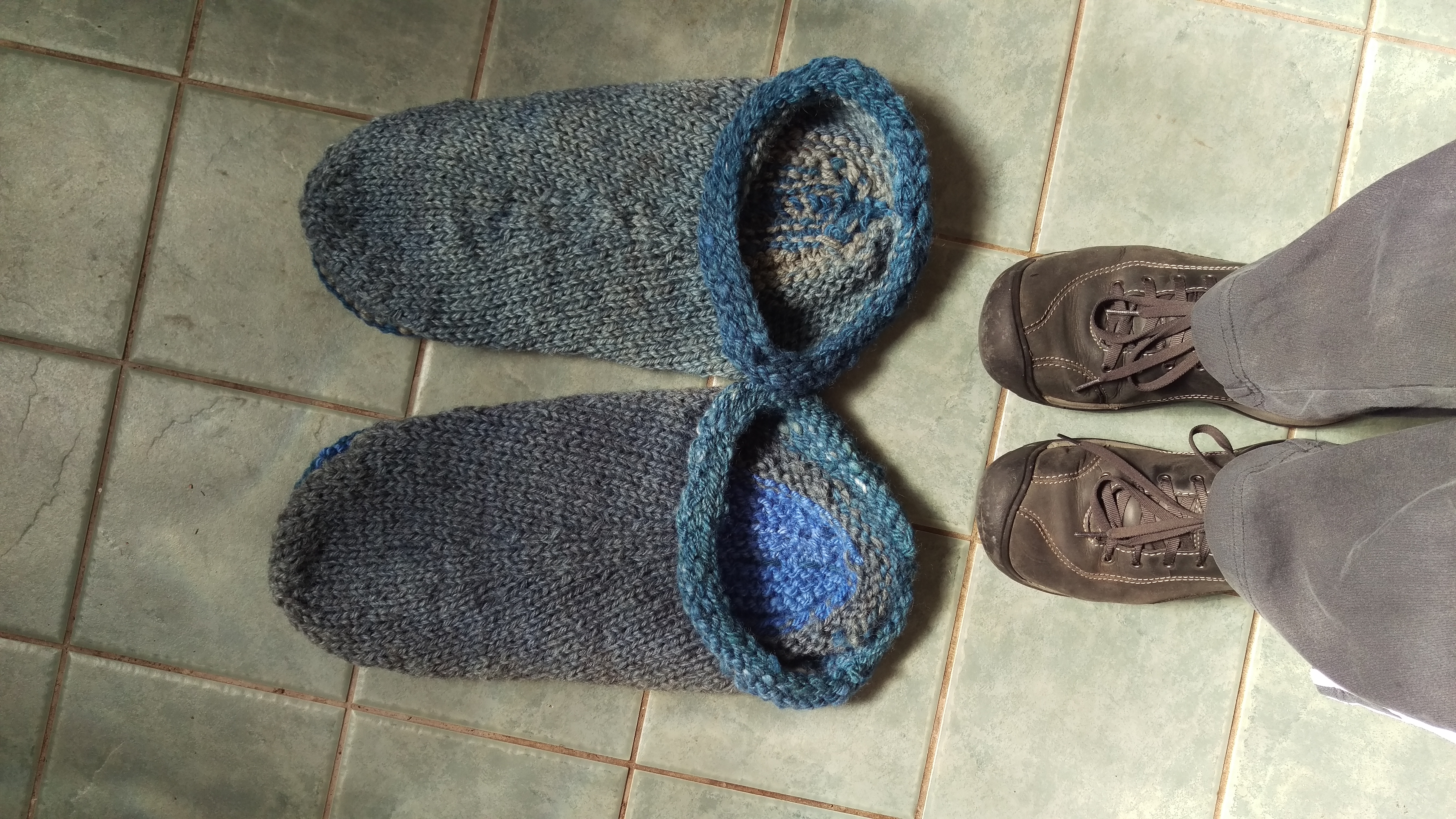 Very large knit slippers prior to felting, with much smaller shoes beside them.